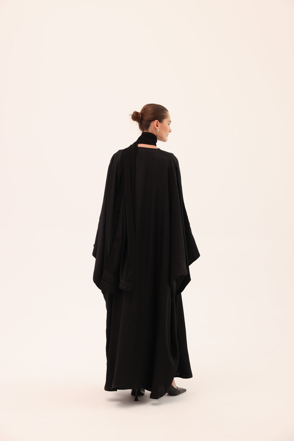Model wearing the ARIA luxury black silk abaya by Tre Sorelle, back view.
