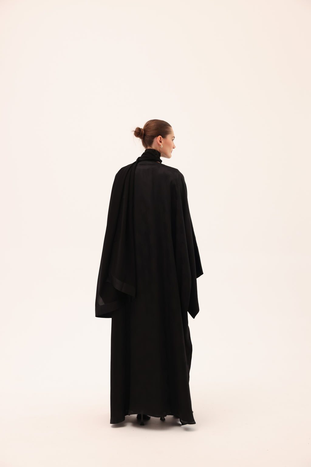 Model wearing the NOTTE luxury black silk abaya by Tre Sorelle, back view.