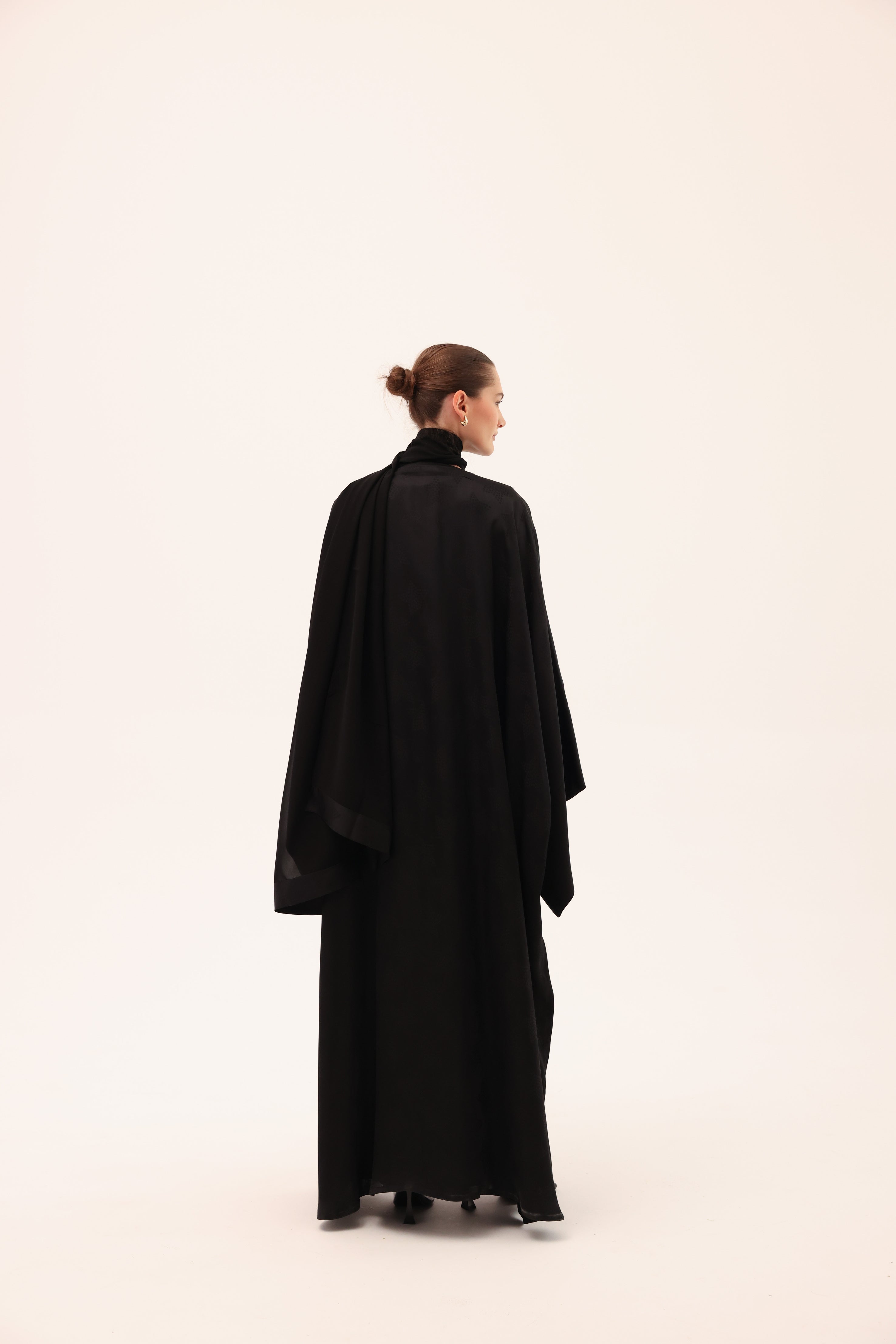 Model wearing the NOTTE luxury black silk abaya by Tre Sorelle, back view.