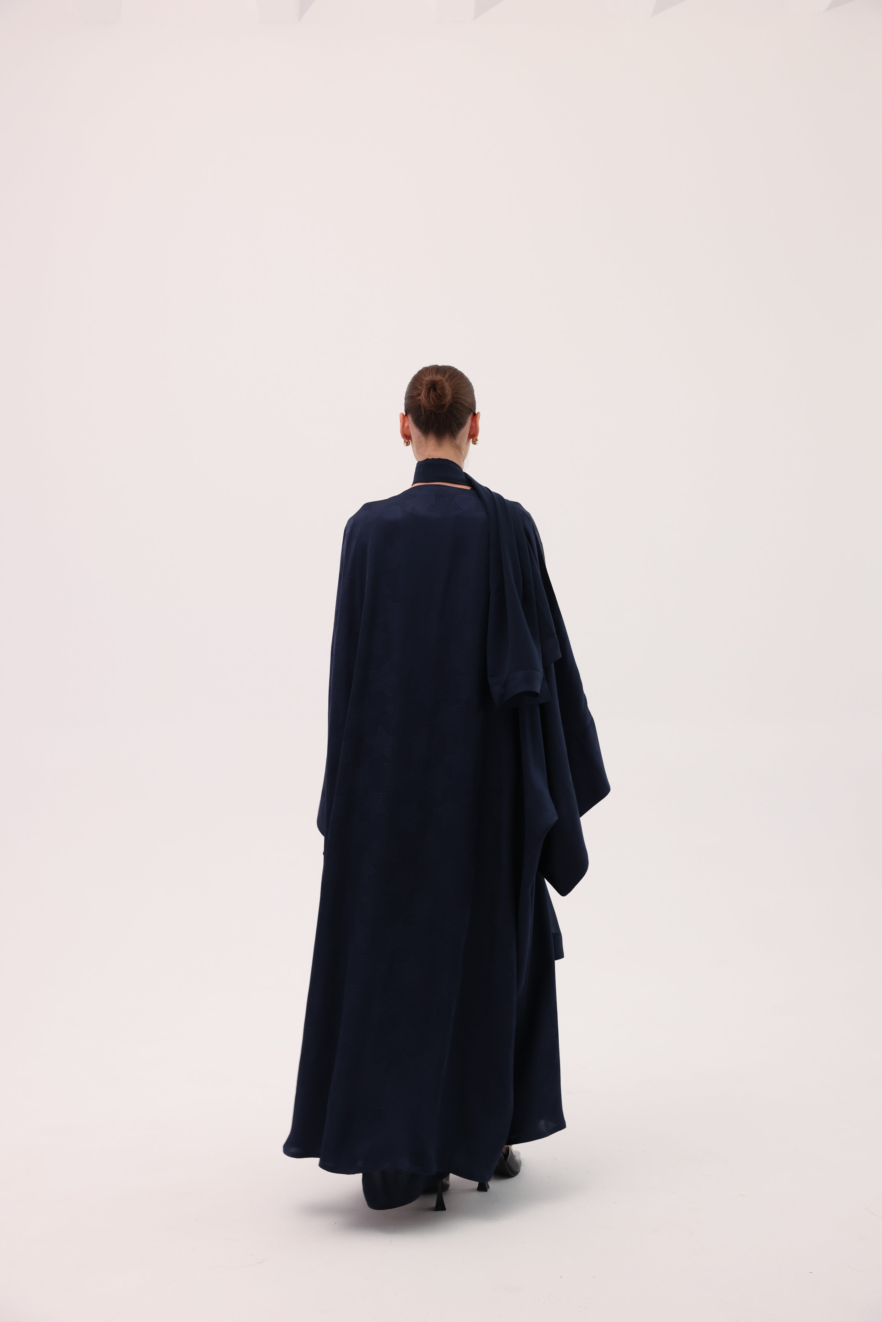 Model wearing the CIELO luxury navy blue silk abaya by Tre Sorelle, back view.